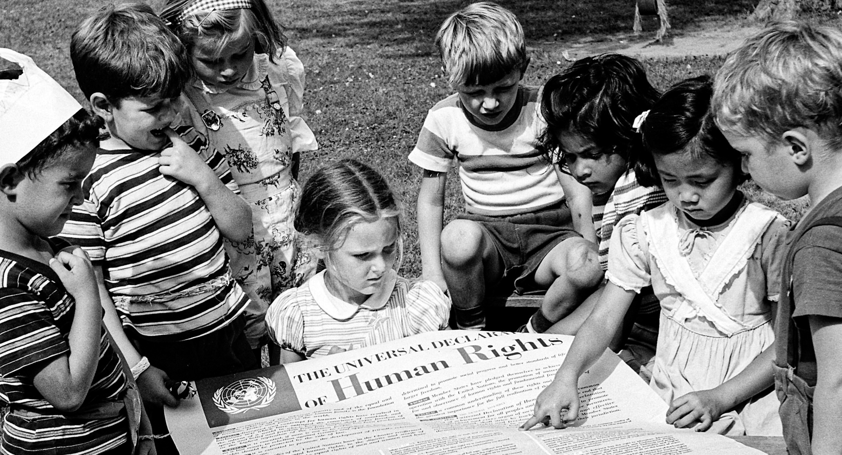 Group of children reading a large poster with the UN's Universal Declaration of Human Rights